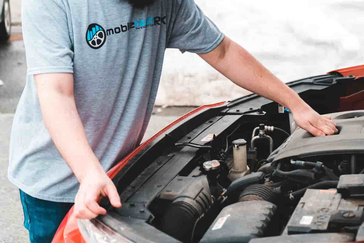 Mobile mechanic working under the hood of a car in a residential driveway — mobile auto repair in Hopkinsville, KY